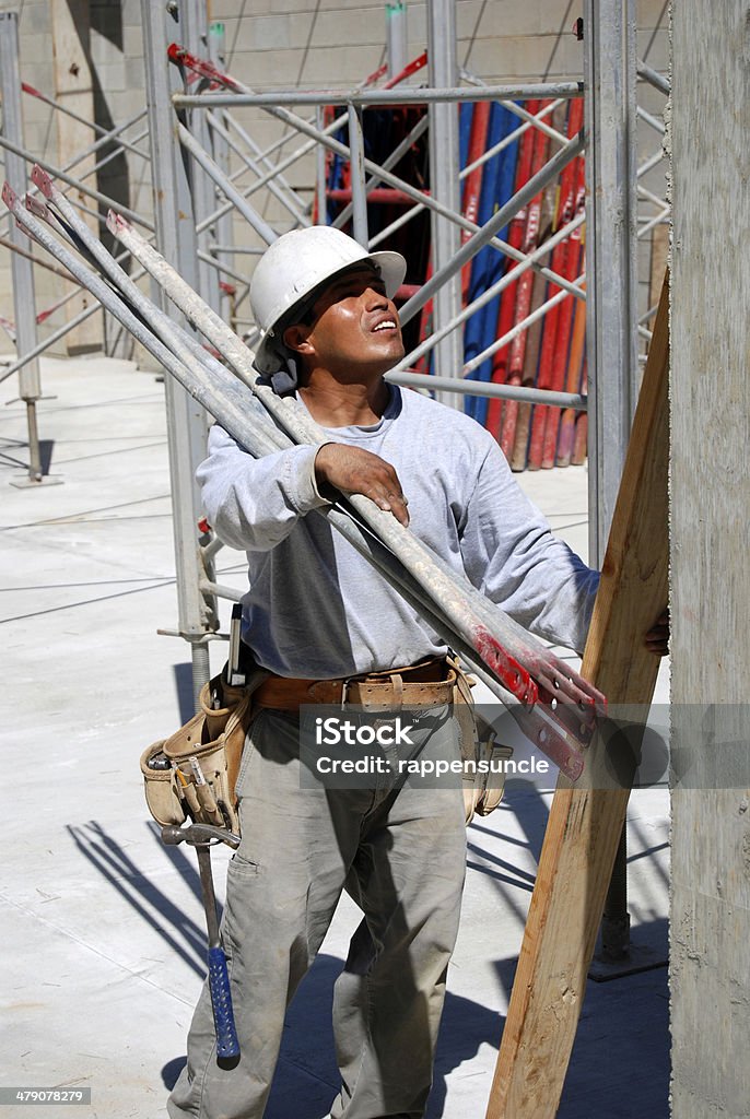 Erecting shoring system A worker carries parts for a shoring system that’s being erected. Activity Stock Photo