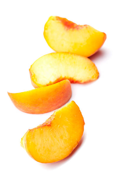 Four fresh peach slices on white background. Focus is on front slice.