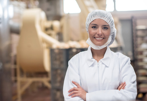 Latin American woman working at a food factory looking at the camera and smiling
