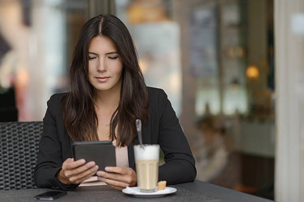 женщина расслабляющий в кофе-бар с ее мобильного - e reader digital tablet cafe reading стоковые фото и изображения