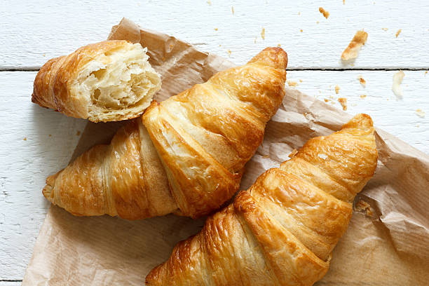 istock Croissants on brown bag on rustic white wood from above. 479108742