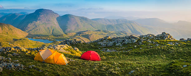 Wild camp tents on mountain top Lake District sunrise panorama Colourful mountain tents pitched on an idyllic wild camp site high in the Lake District National Park, overlooked by the iconic peaks of Great Gable and Green Gable, Cumbria, UK. ProPhoto RGB profile for maximum color fidelity and gamut. langdale pikes stock pictures, royalty-free photos & images