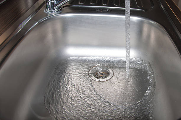 istock Stainless steel sink plug hole close up with water 479115329