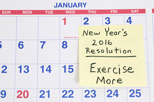 New Years 2016 Resolution reminder to Exercise More written  on a sticky note. The memo note is stuck to a January  calendar page. Shot in studio with Canon 5D Mark II DSLR camera.