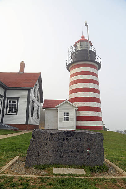 Fogged in Lighthouse Fogged in lighthouse at West Quoddy Head near Lubec Maine with stone marker identifying it as Eastern Most Point in USA. quoddy head state park stock pictures, royalty-free photos & images