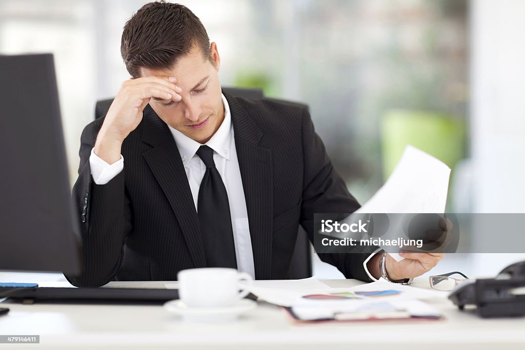 businessman reading documents stressed businessman reading documents in office Adult Stock Photo