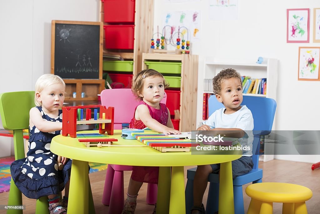 Group Of Toddlers Reading/ Playing With Xylophones Portrait showing a group of toddlers reading and playing with xylophones in a nursery setting. 2-3 Years Stock Photo