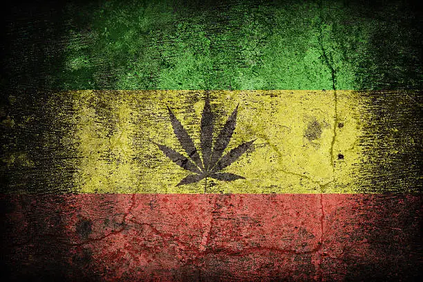 Rasta flag pattern with a marijuana leaf on dirty old concrete wall texture ,retro vintage style