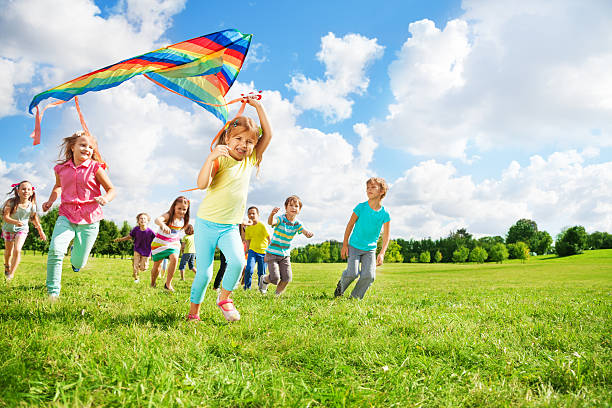 istock Cute group of kids run with kite 479156165