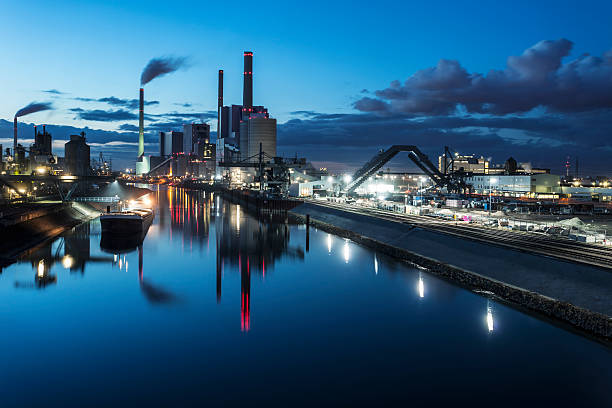 impianti industriali in distanza di notte - industrial district foto e immagini stock