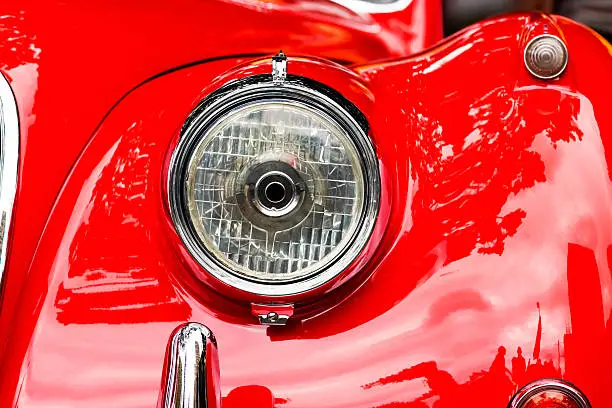 Photo of Closeup headlight of red shiny car