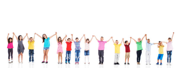 Cheerful children standing in a line and holding hands. Large group of cheerful kids having fun while standing in a line and holding hands. Isolated on white. line of people holding hands stock pictures, royalty-free photos & images