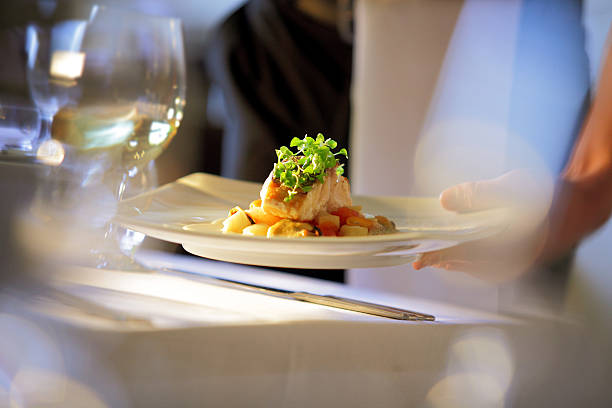 kellner mit essen am tisch - essen am tisch stock-fotos und bilder