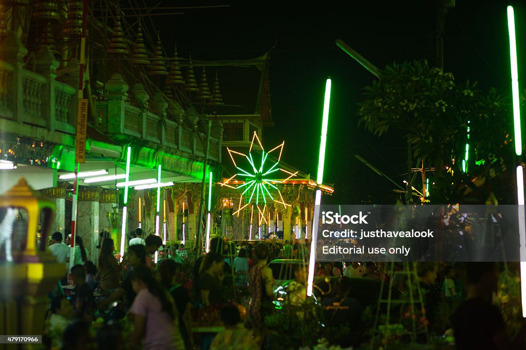 Thai celebrating fullmoon of Makha Bucha Bangkok, Thailand - March 4, 2015: Night shot on grounds of temple Wat Lat Phrao at Wanghin Road. Neon lights are illuminating scene and temple. Fullmoon night and festival of Makha Bucha. Many thai people are visiting temple. In background is neon flower light shape. 2015 Stock Photo