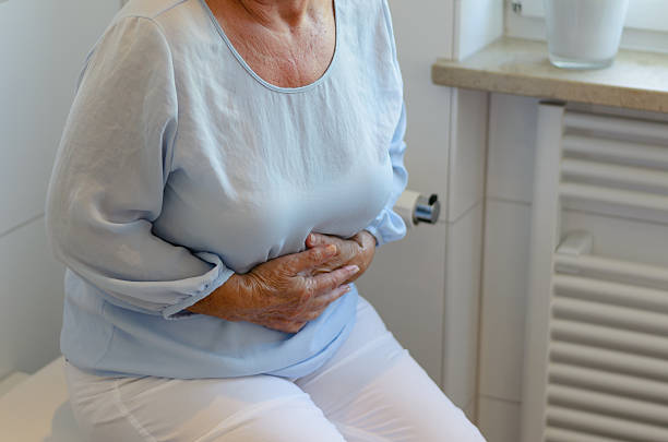 senior mujer sentada en el inodoro - diarrea fotografías e imágenes de stock