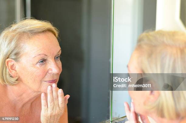 Senior Lady Checking Her Skin In The Mirror Stock Photo - Download Image Now - 2015, Adult, Aging Process