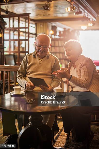 Smiling Seniors Using Digital Tablet In A Cafe Stock Photo - Download Image Now - 2015, 60-69 Years, Active Seniors
