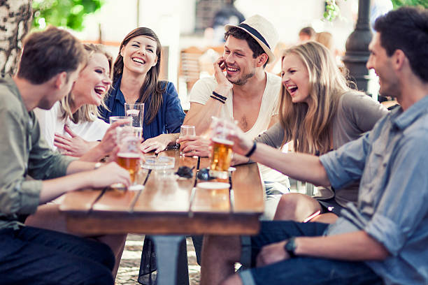 Young people drinking beer outdoors Group of young cheerful people having fun drinking beer outdoors. blond hair fine art portrait portrait women stock pictures, royalty-free photos & images