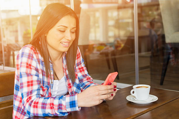 jeune femme avec son smartphone dans le café-restaurant - red text messaging cafe teenage girls photos et images de collection