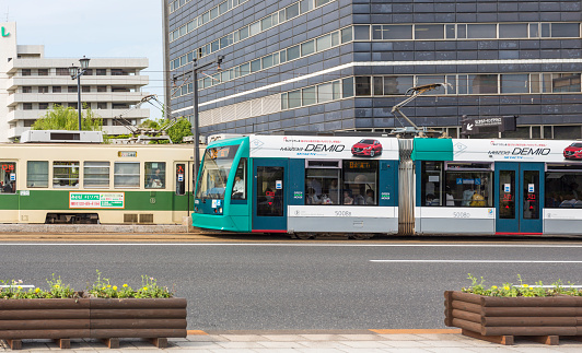 Hiroshima, Japan - May 22, 2015: Two public transport trams loaded with commuters pass each other on the street in Hiroshima, Japan