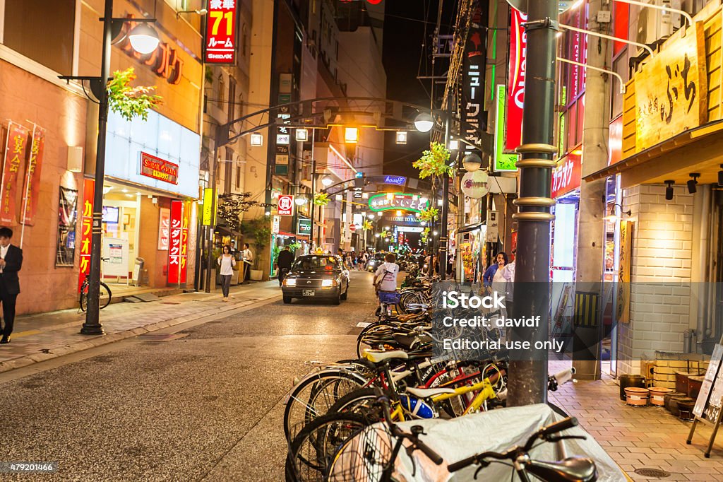 People On A Brightly Lit Shopping Street in Hiroshima Hiroshima, Japan - May 22, 2015: People walking along a shopping street in Hiroshima lit by large bright signs for local businesses City Street Stock Photo