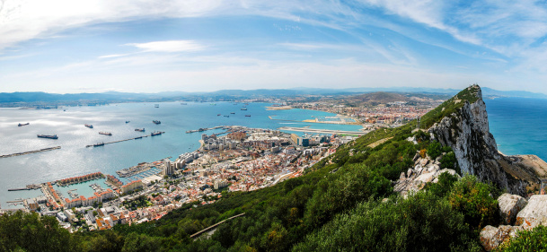 Gibraltar Rock view from above, on the left Gibraltar town and bay, La Linea town in Spain at the far end, Mediterranean Sea on the right.