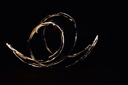 A Poi performer, myself actually, shot with a long exposure capturing the movement of the poi at different stages of the dance.