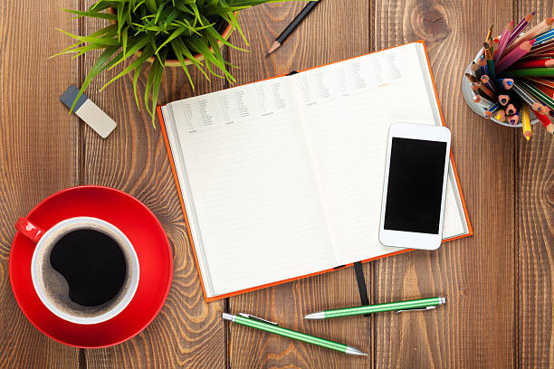 Office desk table with supplies, coffee cup and flower. Top view with copy space