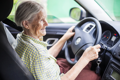 Senior woman driving a car and smiling