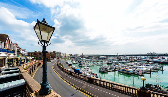 A view across Ramsgate Harbour, a popular tourist destination and port. Cafe seating on the left and a nice old lamp post.