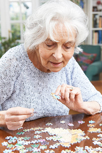Senior Woman Relaxing With Jigsaw Puzzle At Home