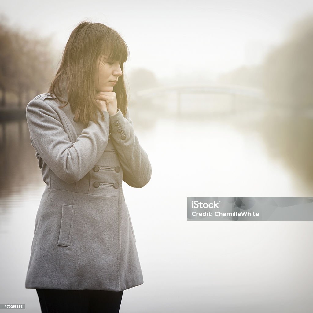 pretty sad girl near river in a fog young pretty sad girl in cold weather near river in a fog Cold Temperature Stock Photo