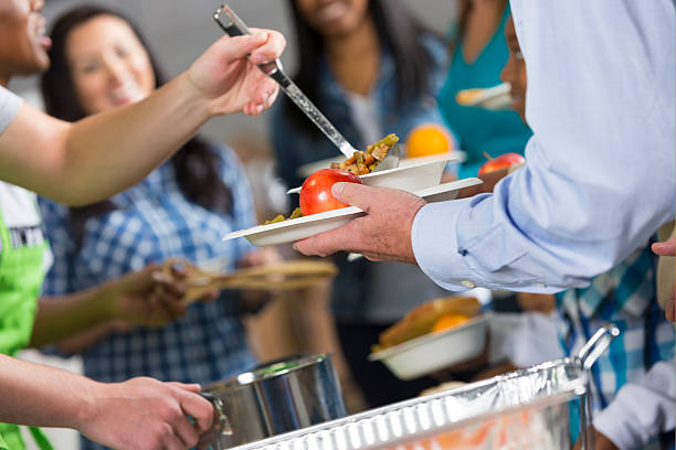 istock Volunteers serving hot meal to people at community soup kitchen 479217329
