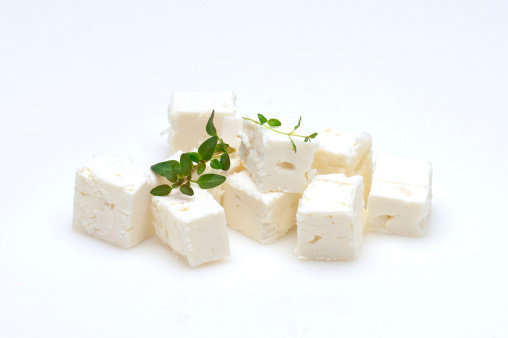 feta cheese cubes and oregano on a white background