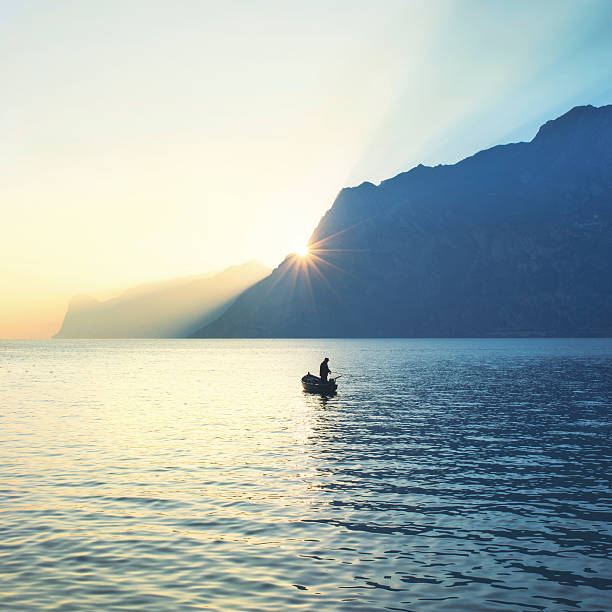 homme sur un canoë de la pêche, sous un superbe coucher de soleil - sea zen like landscape water photos et images de collection