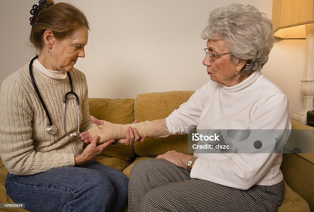 Home healthcare médecin examiner enveloppé poignet de femme âgée - Photo de Troisième âge libre de droits