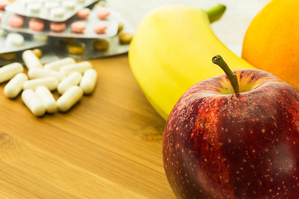различные свежие фрукты и витамин таблетки - capsule vitamin pill red orange стоковые фото и изображения