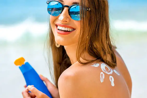 Photo of Woman using sun cream on the beach