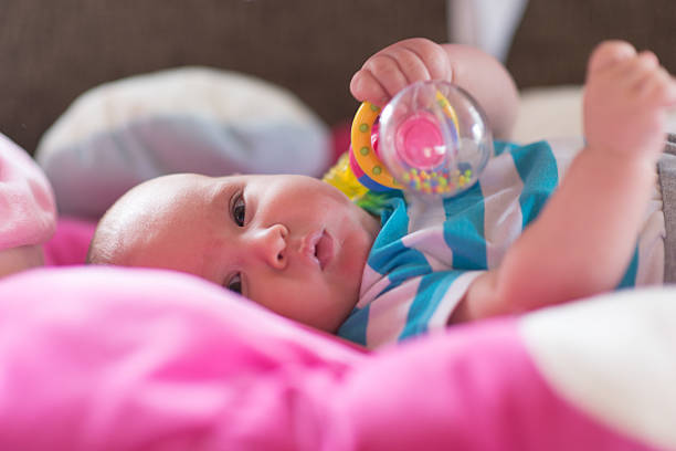istock Baby playing with toy rattle lying on back 479244288