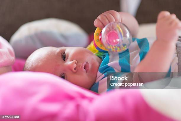 Baby Playing With Toy Rattle Lying On Back Stock Photo - Download Image Now - 0-11 Months, 2015, Babies Only