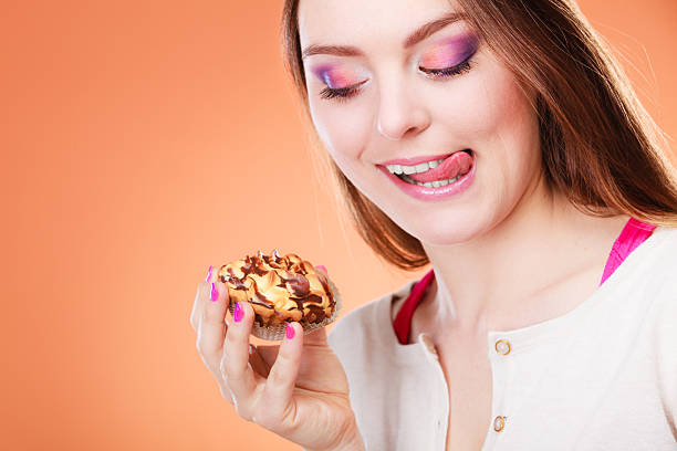 istock woman holds cake in hand licking lips 479244840