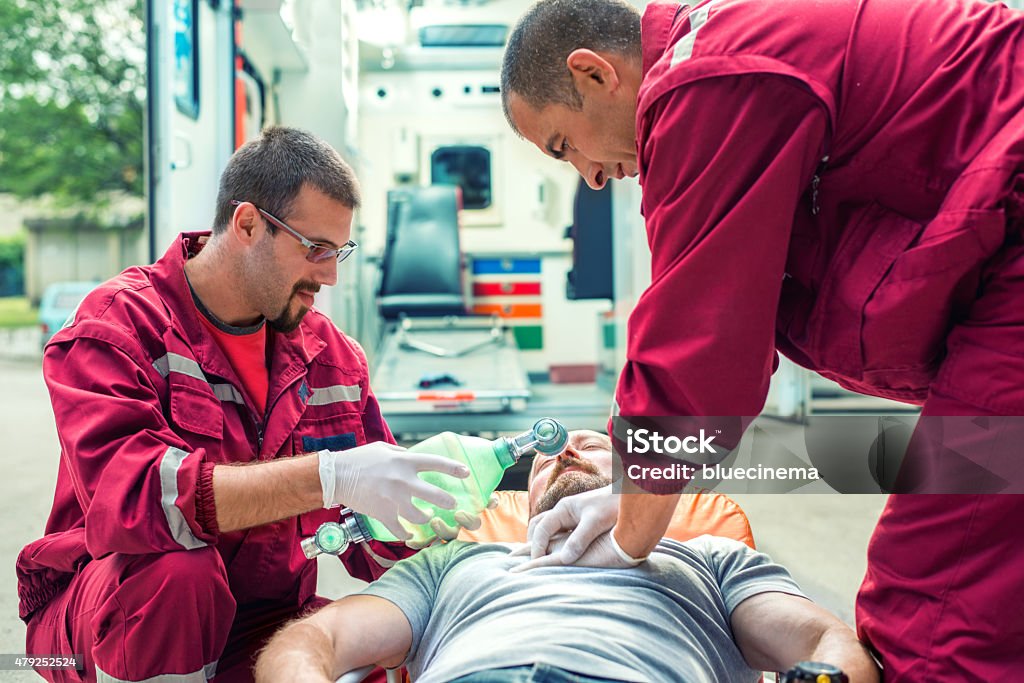 Emergency service rescuing an infarcted A photograph of two medical professionals helping injured man City Stock Photo