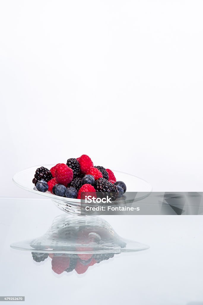 Bramble in the glass bowl Raspberry & blueberry & blackberry in the glass bowl on the glass table 2015 Stock Photo