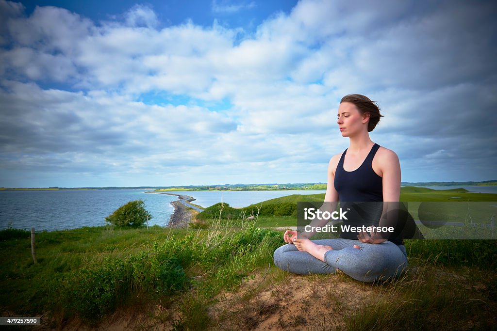 Doing yoga by the sea Young woman practice yoga outdoors in nature on a spring day overlooking the sea. 20-29 Years Stock Photo