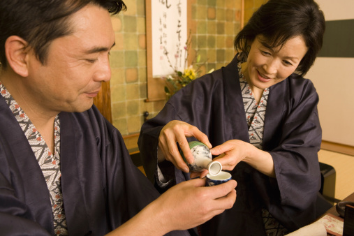 Husband and wife in yukata pouring out alcohol drink