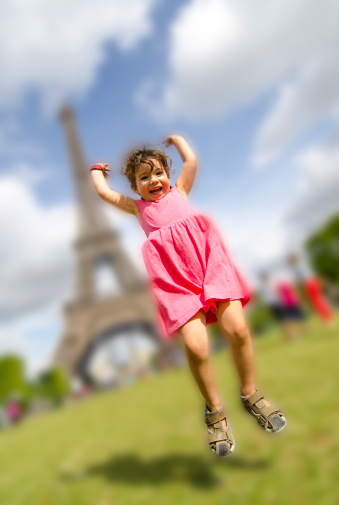A young girl jumping with the Eiffel Tower in background