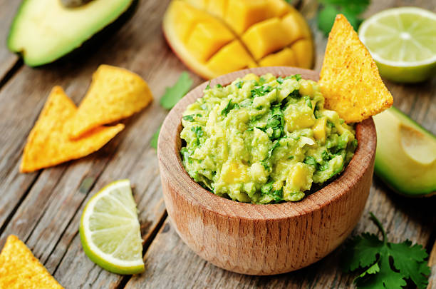 mango guacamole with corn chips mango guacamole with corn chips on a dark wood background. the toning. selective focus guacamole stock pictures, royalty-free photos & images