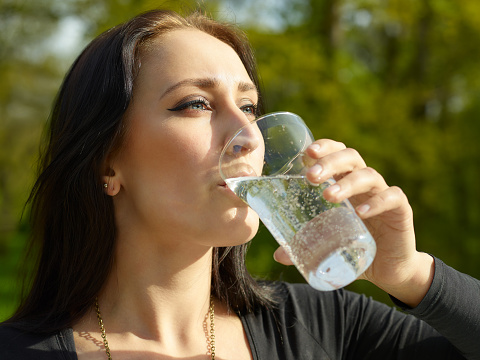 Woman with glass of sparkling water, sunny summer day
