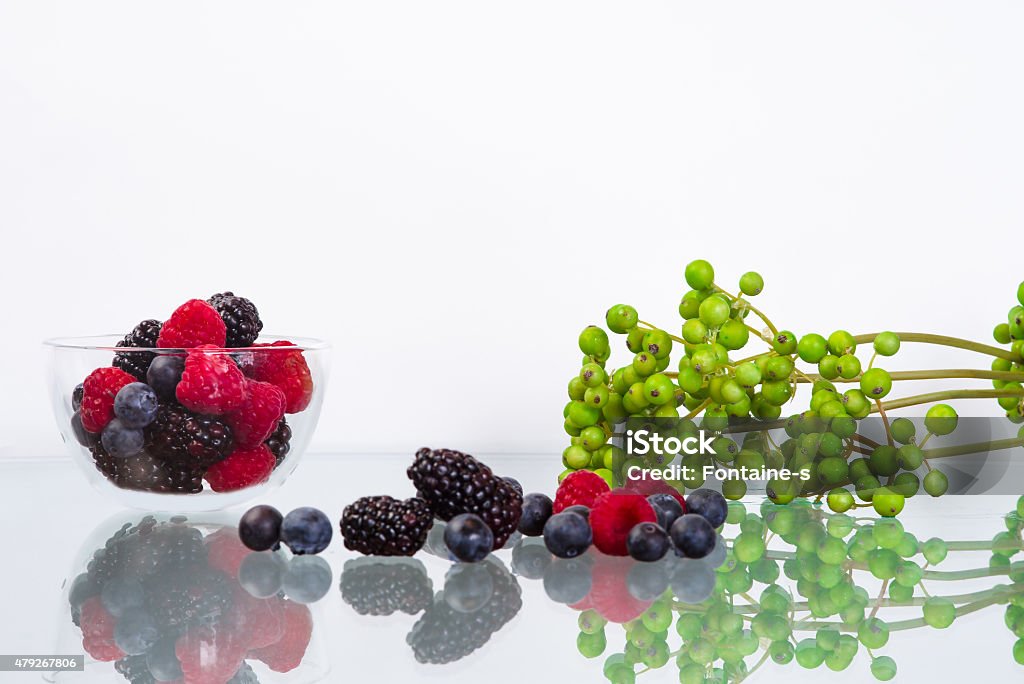 Bramble in the glass bowl Raspberry 6 blueberry 6 blackberry in the glass bowl on the glass table with green 2015 Stock Photo