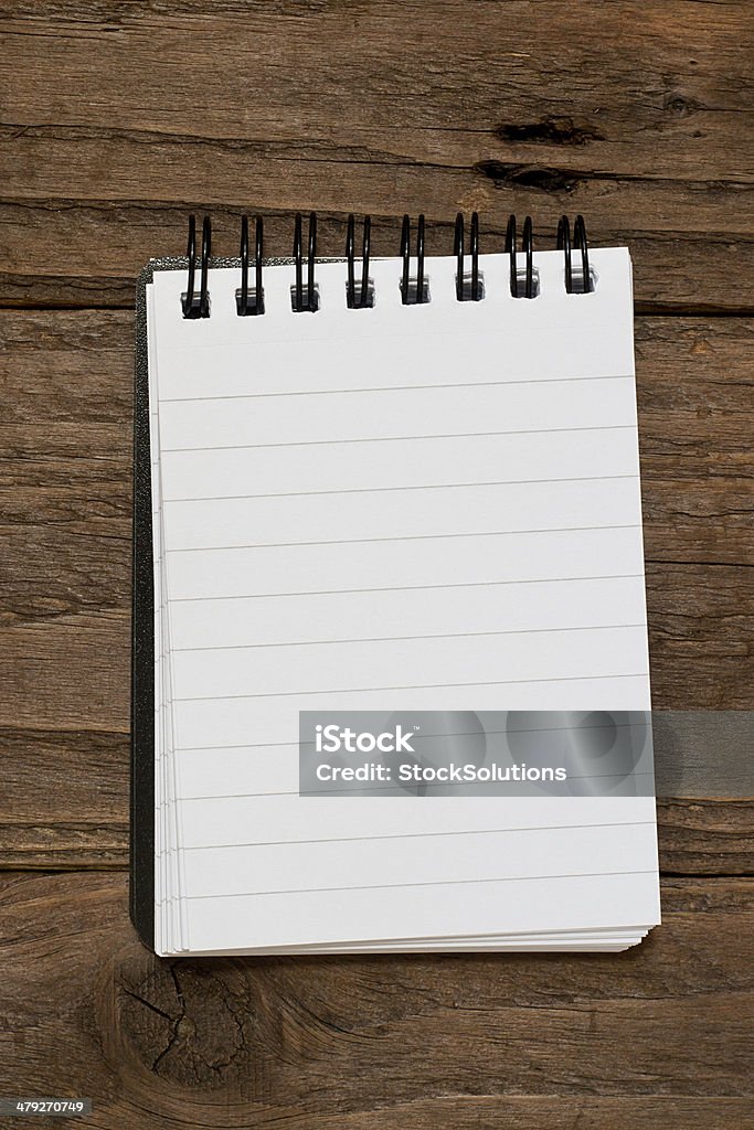 Small lined notepad Small pocket sized notepad on a rustic wooden background with blank space for inserting your own message or note. Small Stock Photo